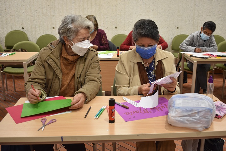 Mujeres mayores cortando papel con unas tijeras en la biblioteca