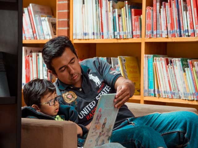 Adulto y niño leyendo en la biblioteca