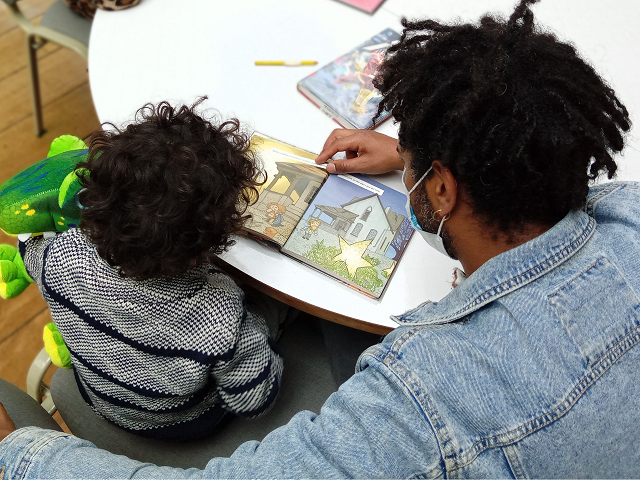 Hombre y niño afro leyendo en la biblioteca