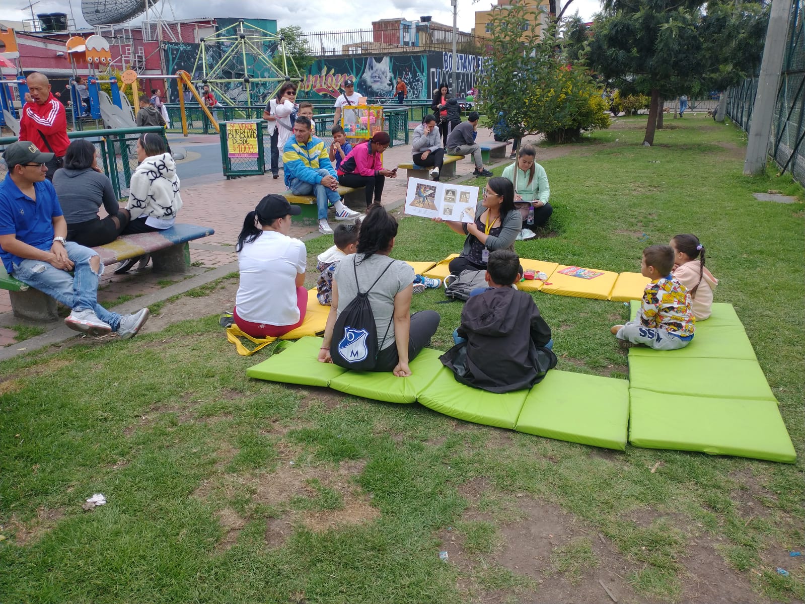 Niños, jóvenes y adultos leyendo en un parque