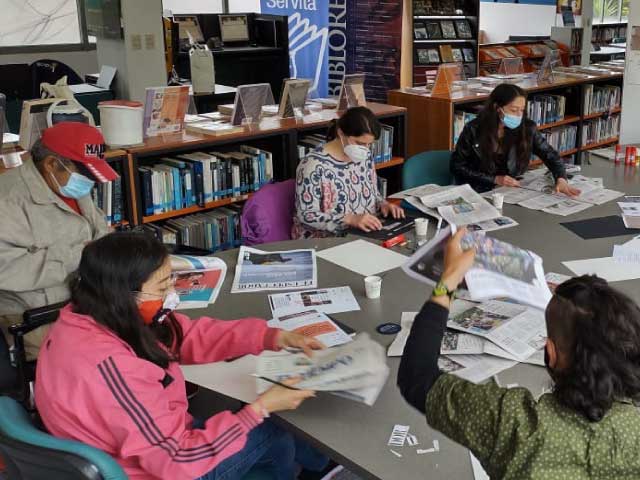 personas cortando periódicos en una actividad en la biblioteca