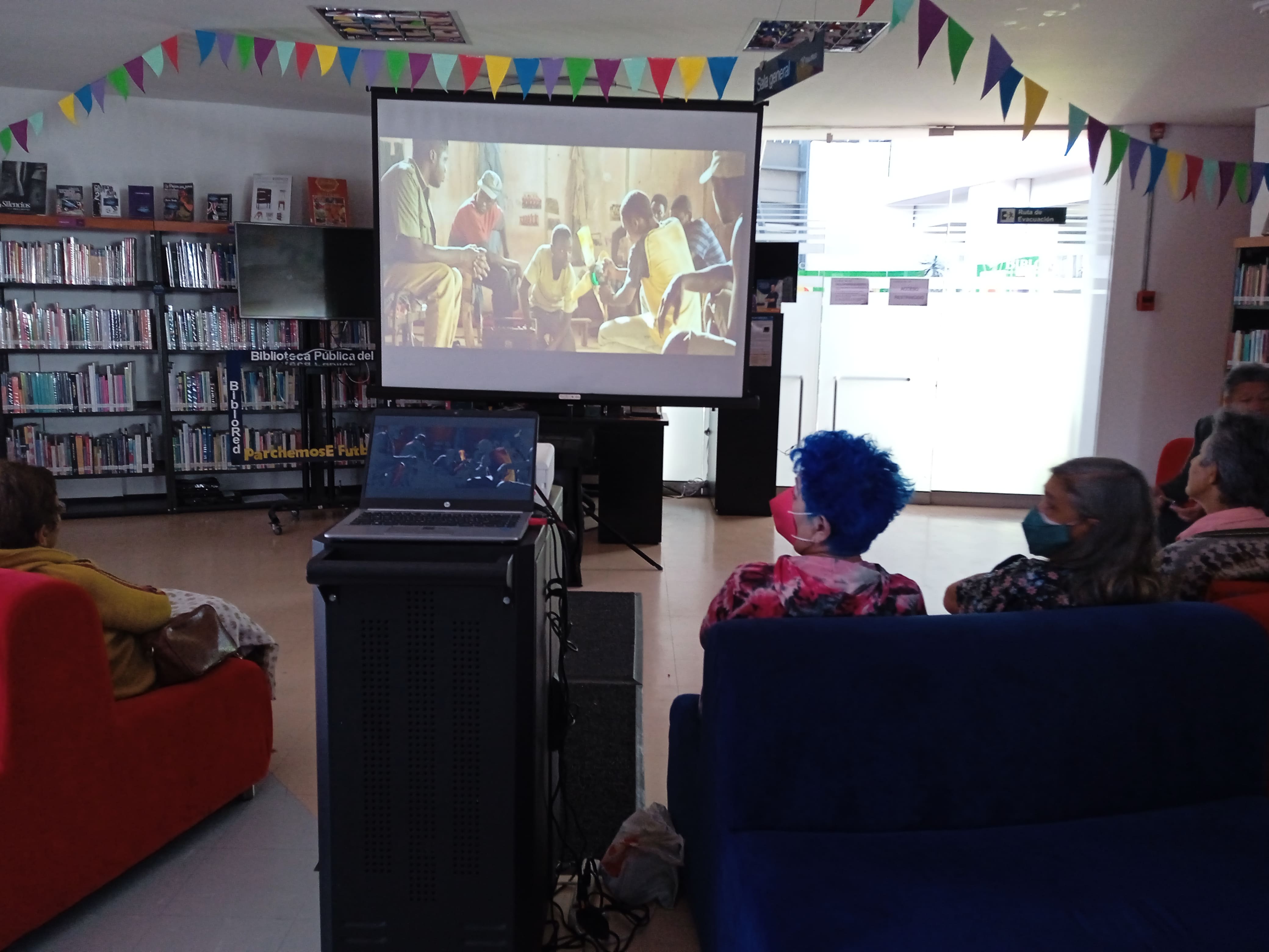 Personas viendo una película en la biblioteca