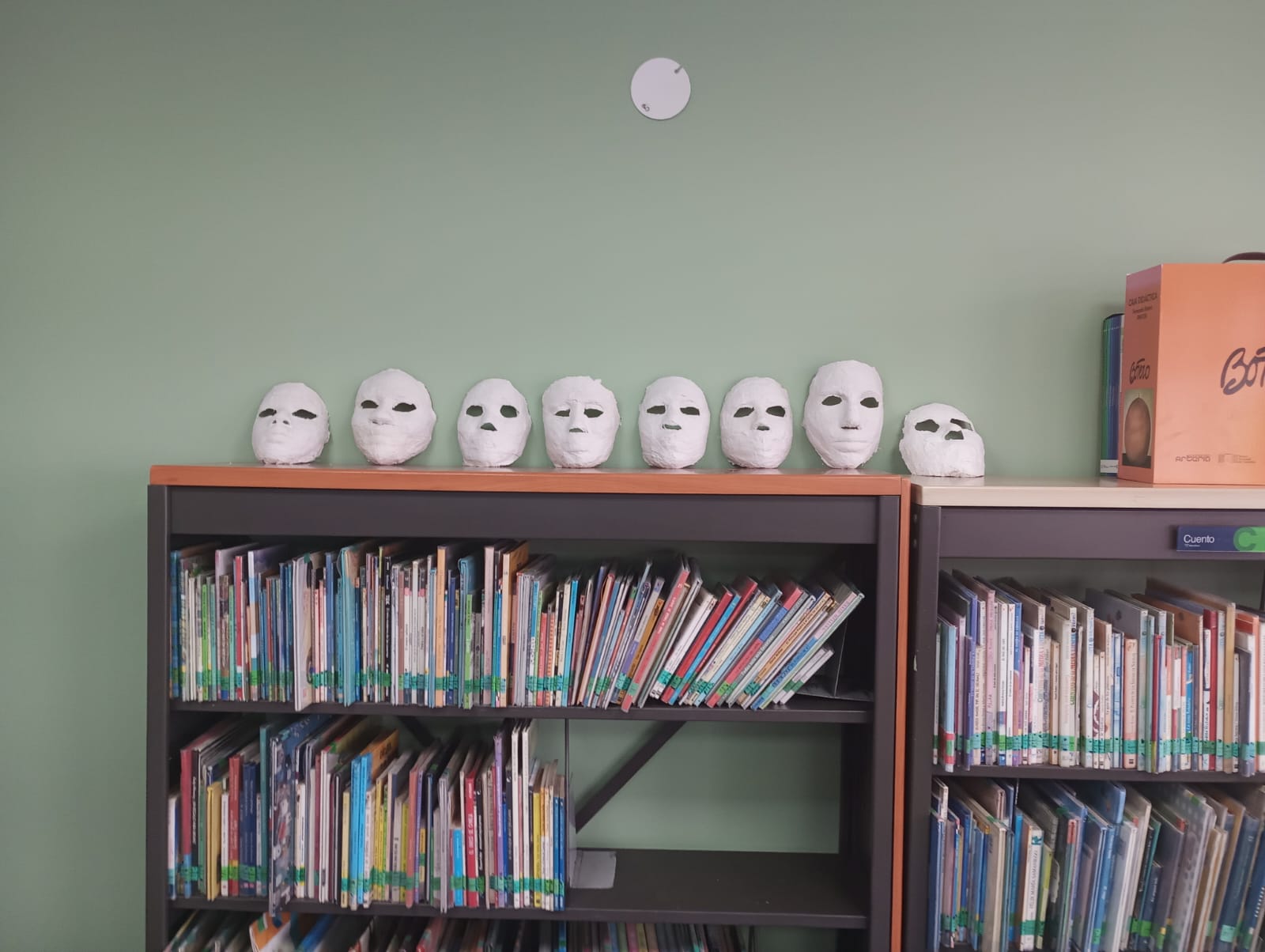 estante con libros y mascaras de papel en la biblioteca