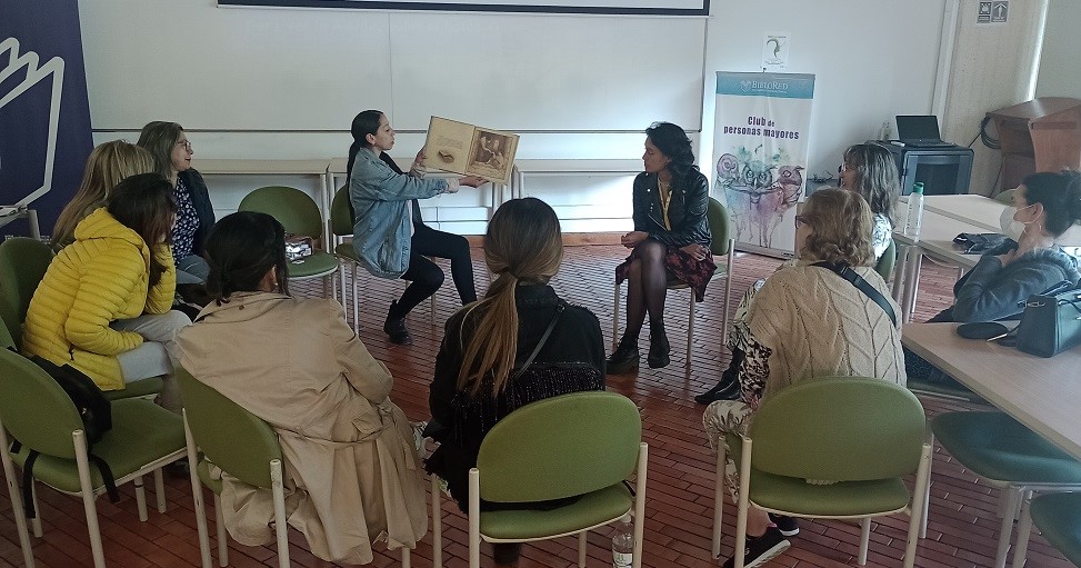 Mujeres reunidas en la biblioteca mientras leen en voz alta