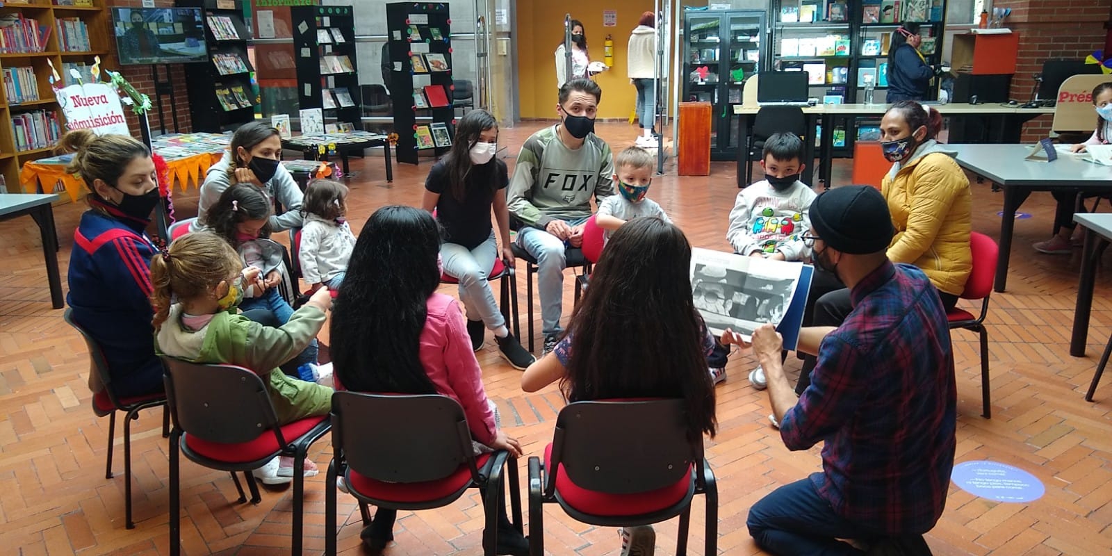 grupo de niños y niñas junto a sus cuidadores en medio de un conversatorio.