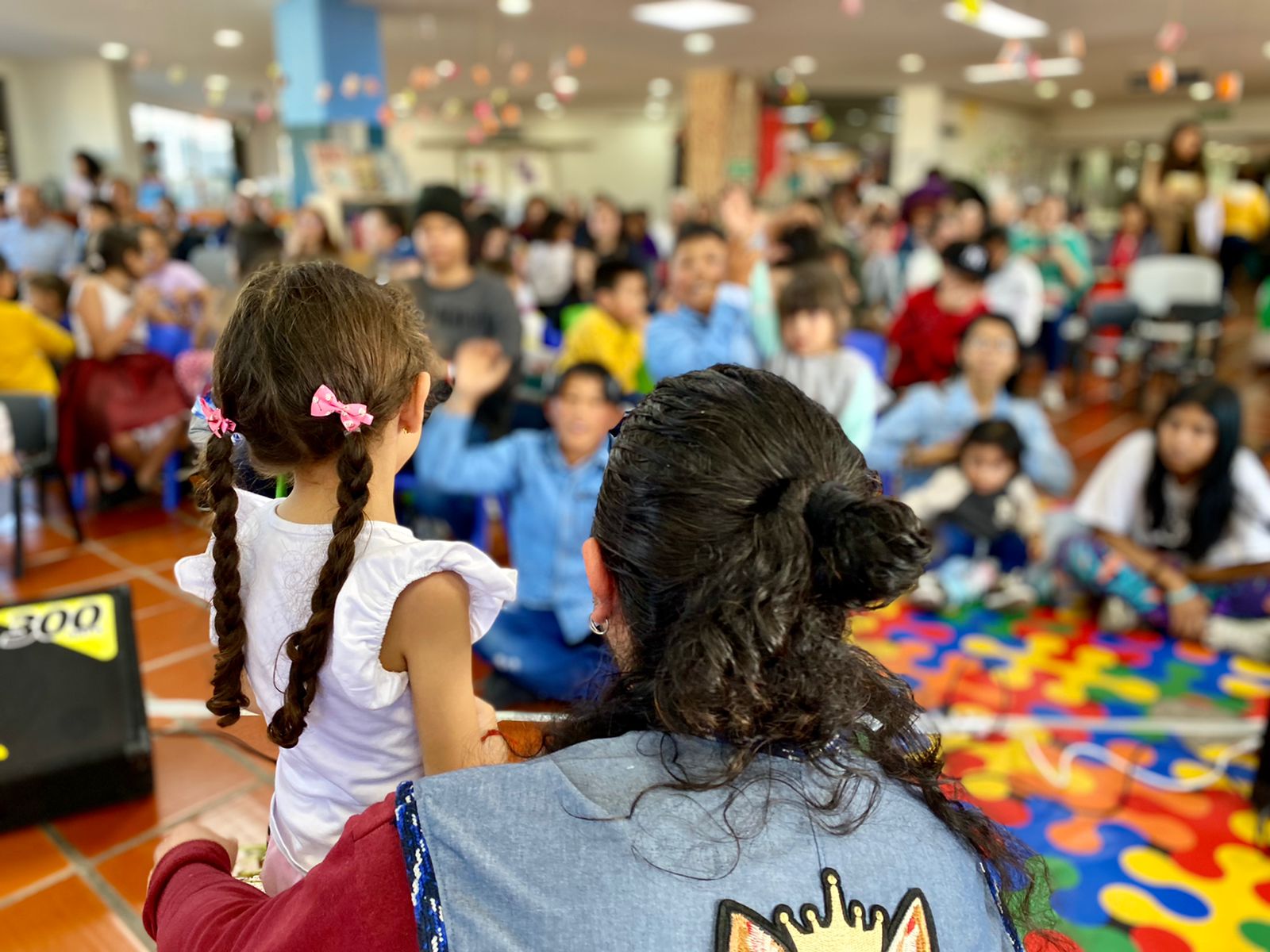 Niñas, niños y adultos participando de actividad en la biblioteca