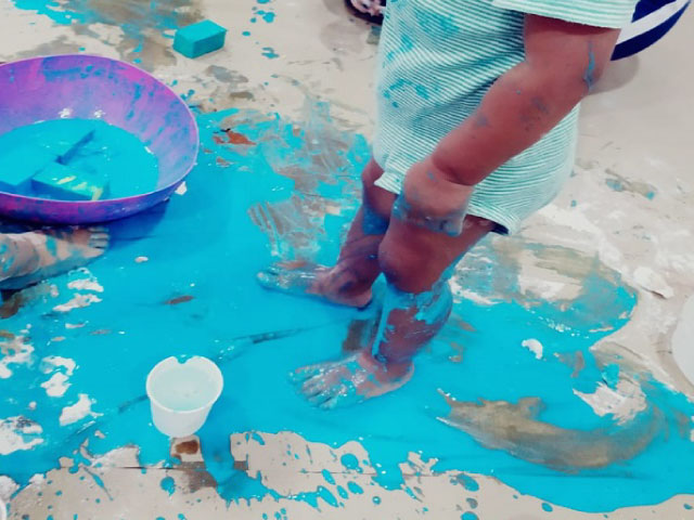 niño pequeño jugando con pintura azul.