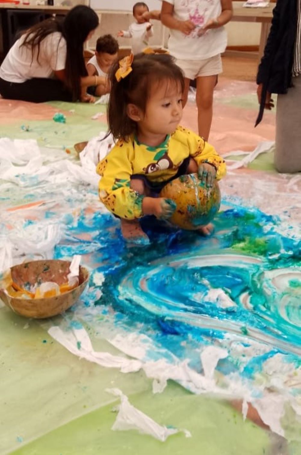 niña jugando con pintura azul sobre el suelo