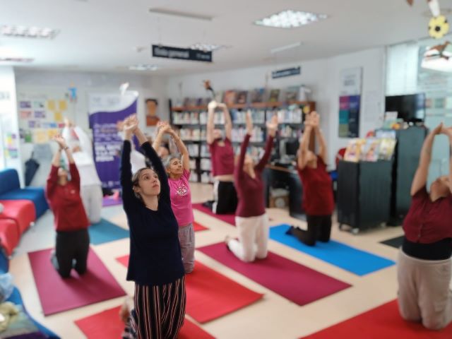 Adultos participando en actividad de yoga en la biblioteca