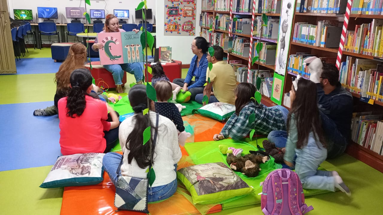 Niñas. niños y adultos participan de actividad en la biblioteca