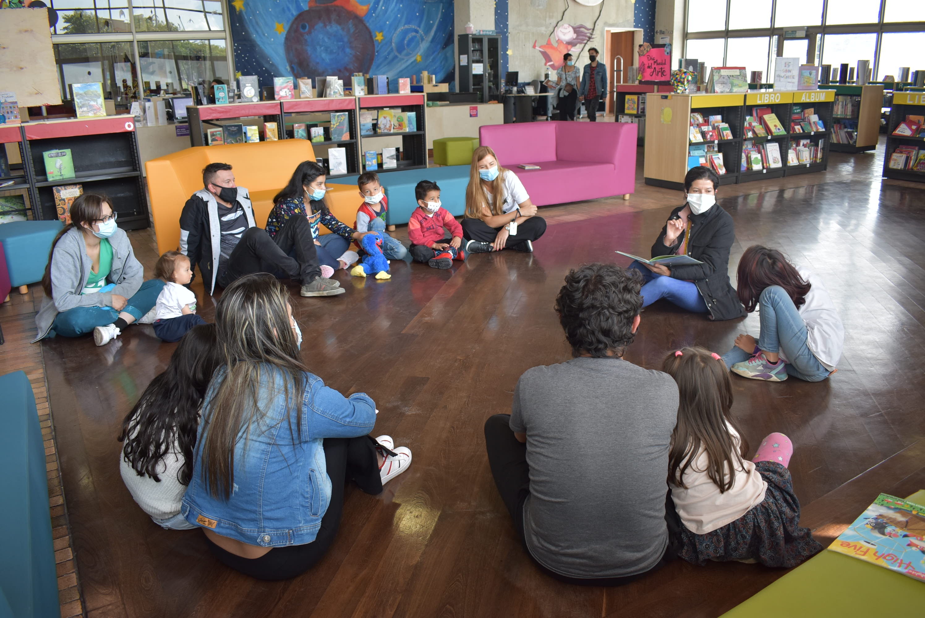 niños junto a sus padres sentados en círculo jugando 