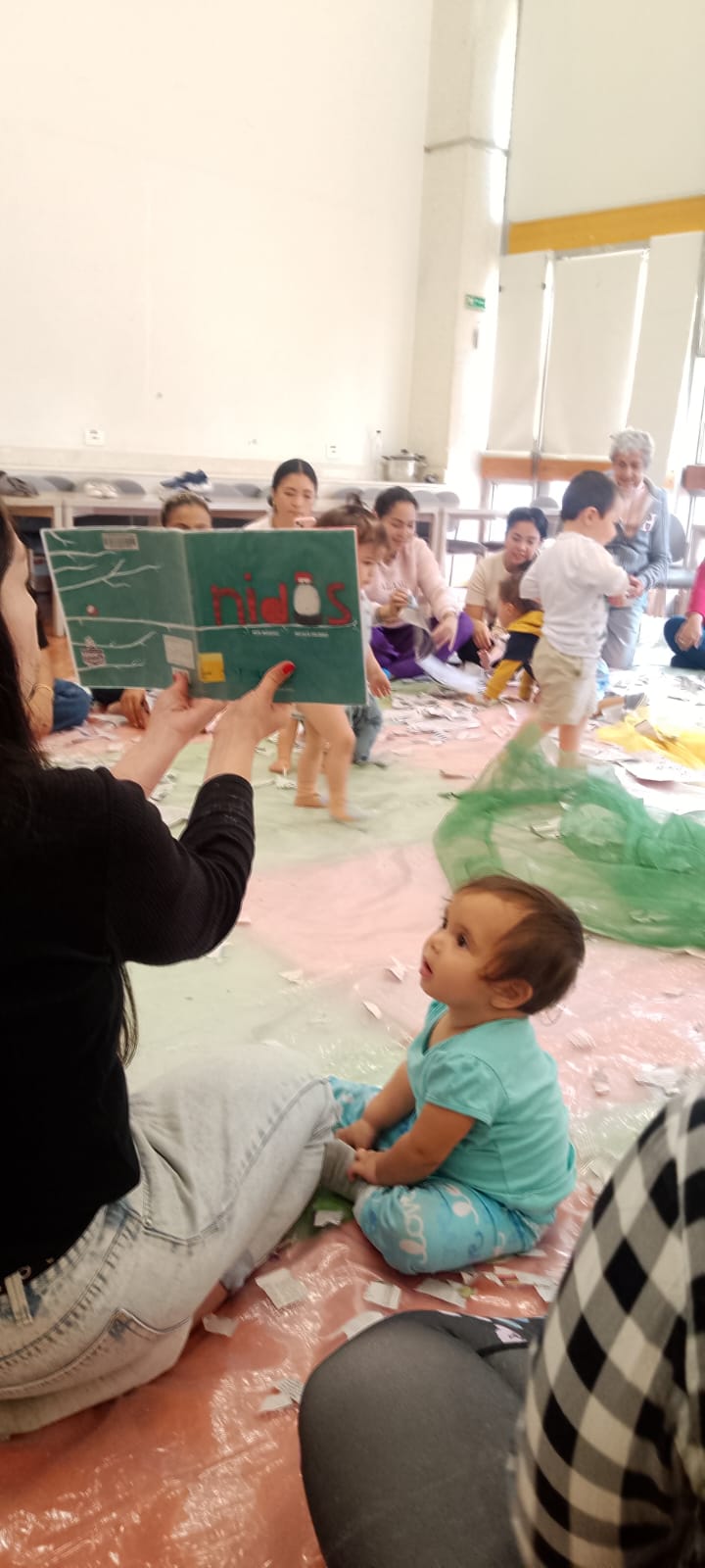 Un niño pequeño prestando atención al libro que le esta mostrando la docente 