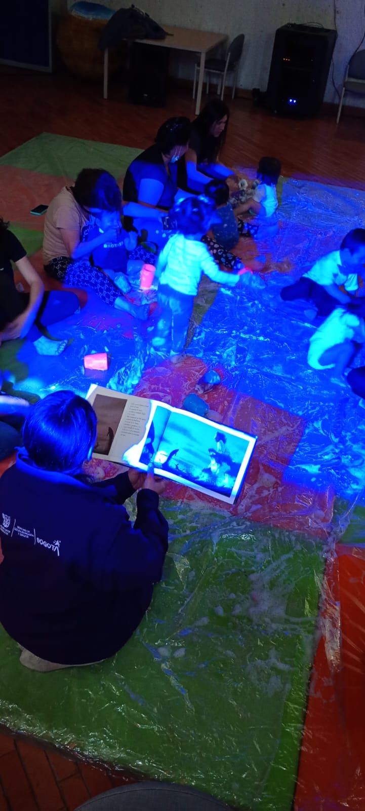 niños jugando y leyendo junto a sus acompañantes bajo la luz azul