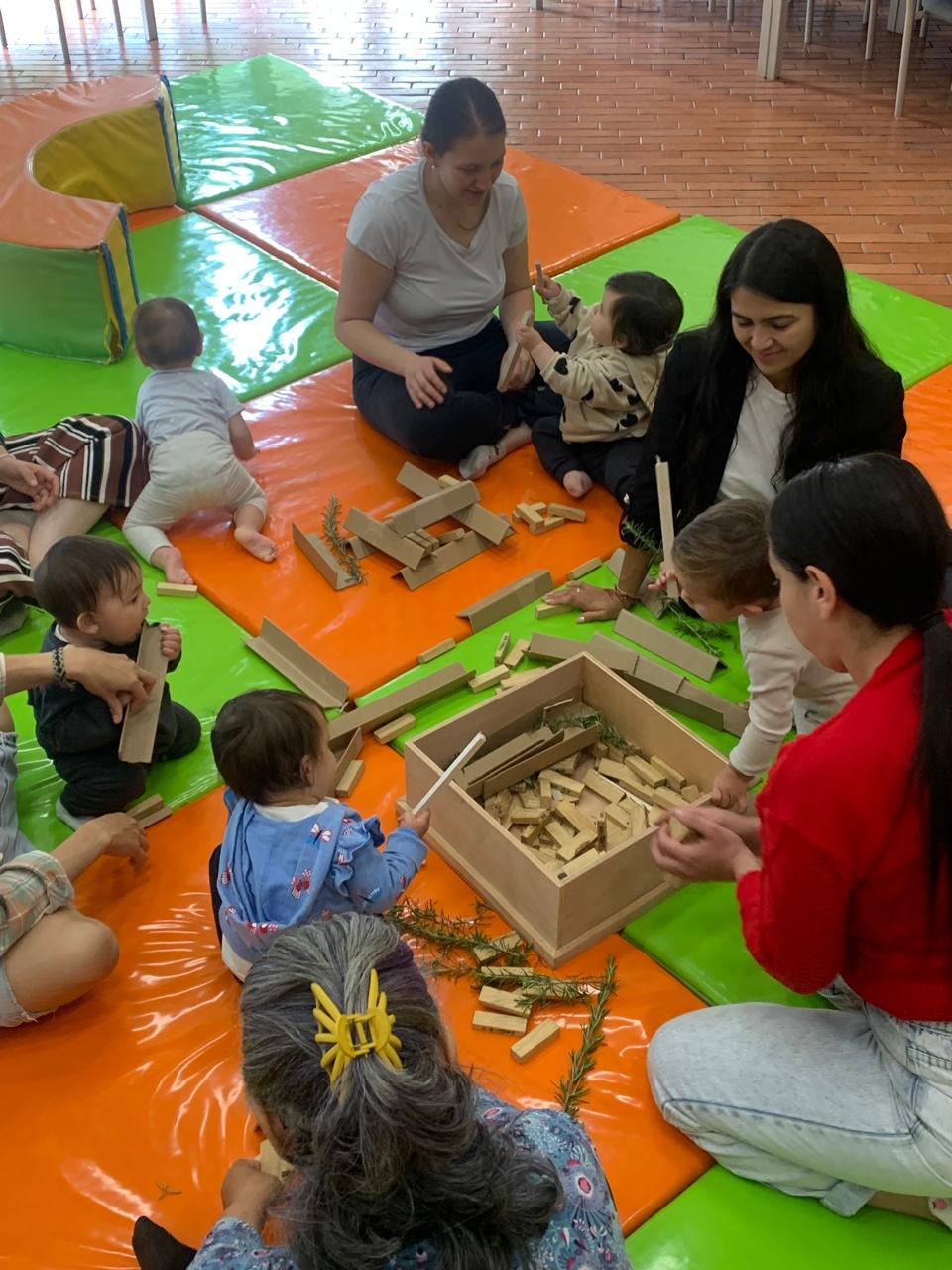 grupo de mamás jugando junto a sus acompañantes con piezas de madera