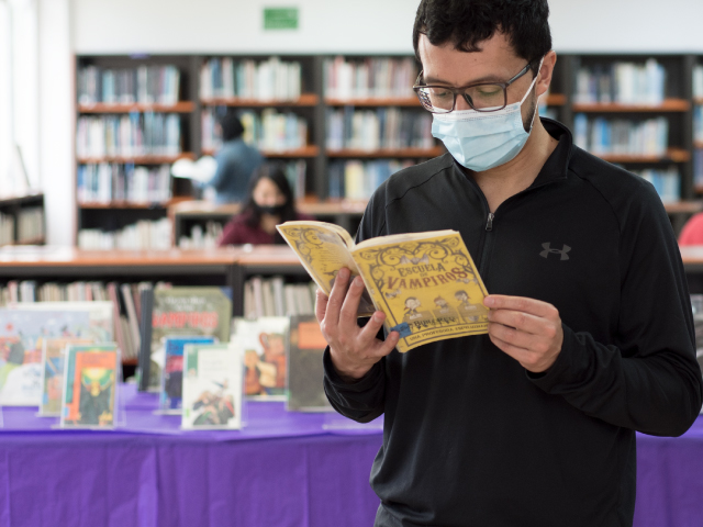 un hombre leyendo un libro en medio de la sala de una biblioteca