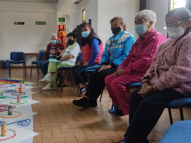 grupo de adultos esperando que inicie una actividad de manualidades