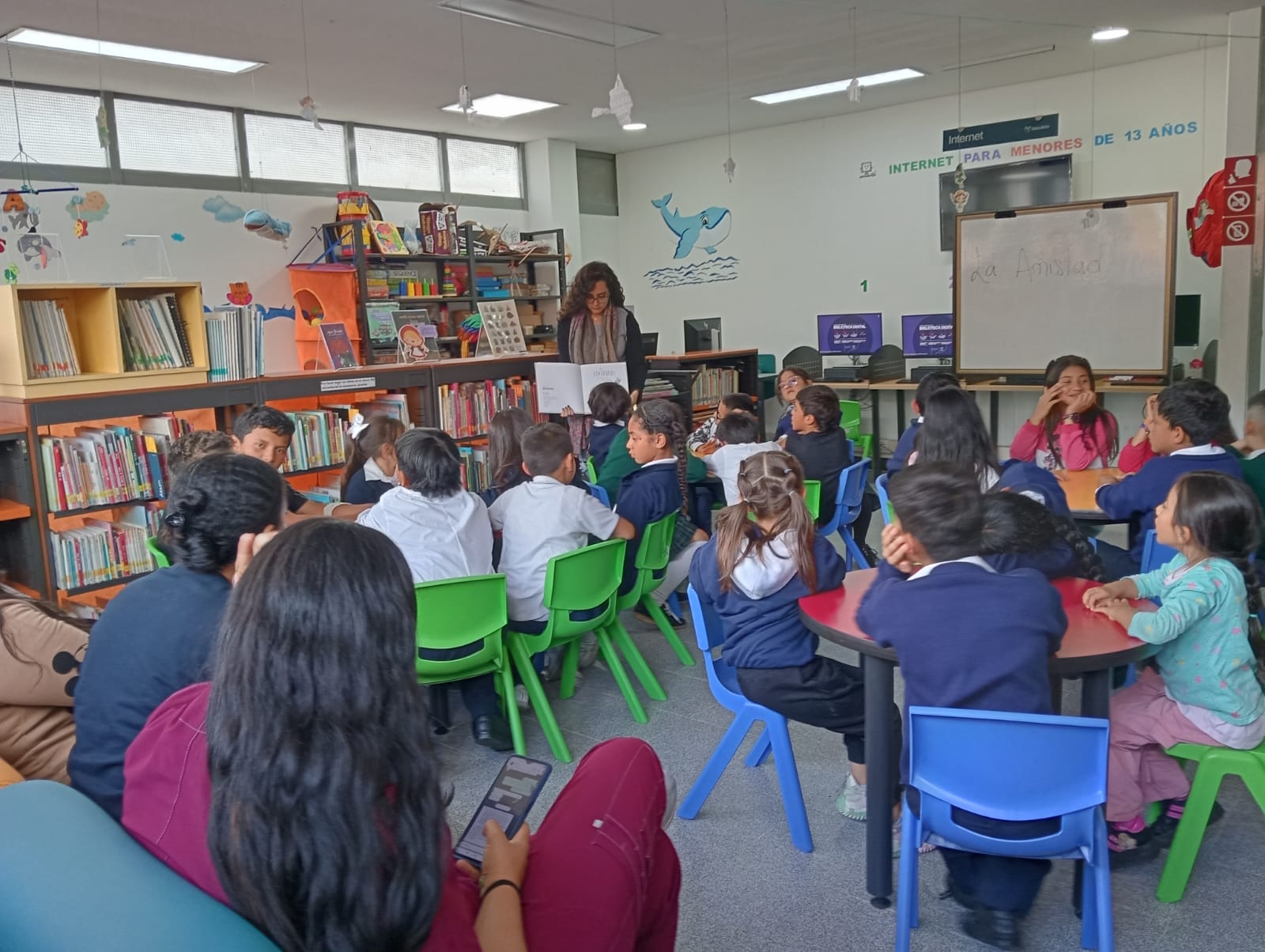 grupo de niños y niñas leyendo en voz alta junto a su profesora