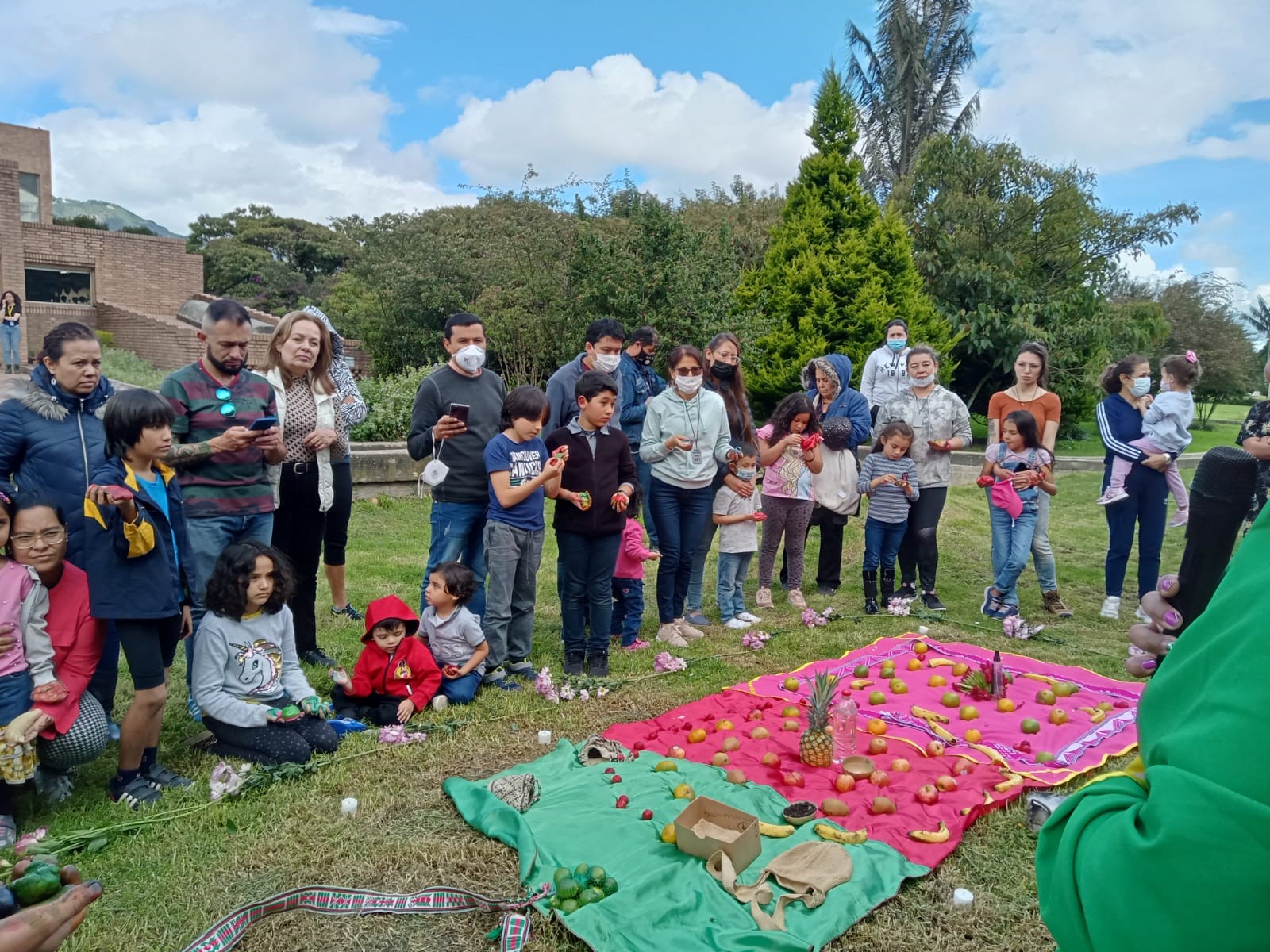 grupo de personas reunidas al frente de mantas de colores con comida 