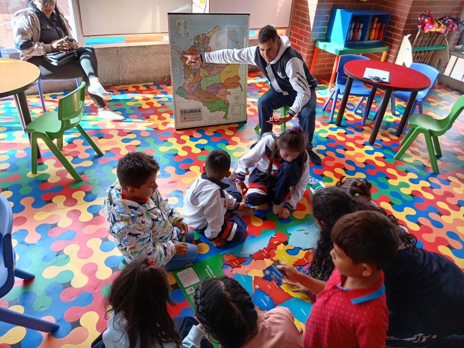 grupo de niños prestando atención al docente que les enseña el mapa de Colombia