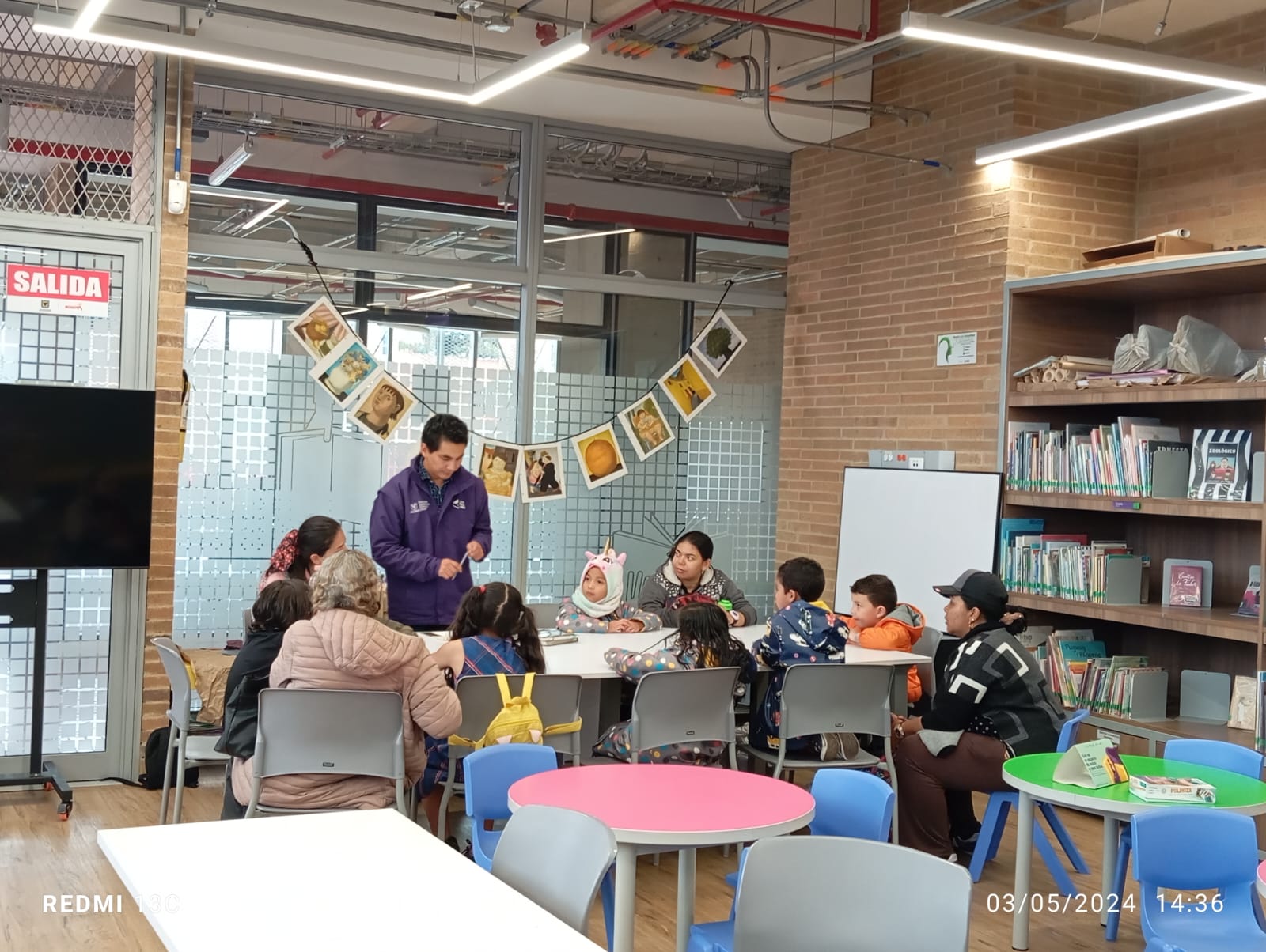 Infancias y sus cuidadores participando en el club de lectura infantil en la biblioteca