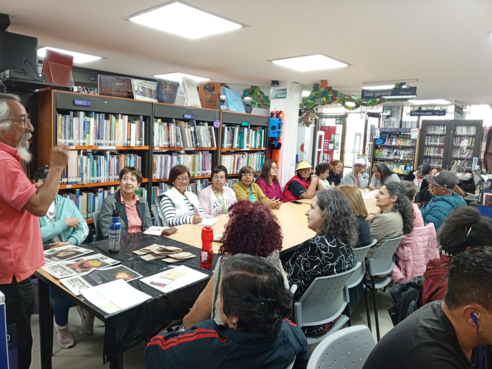 grupo de adultos mayores en medio de un taller prestándole atención al docente