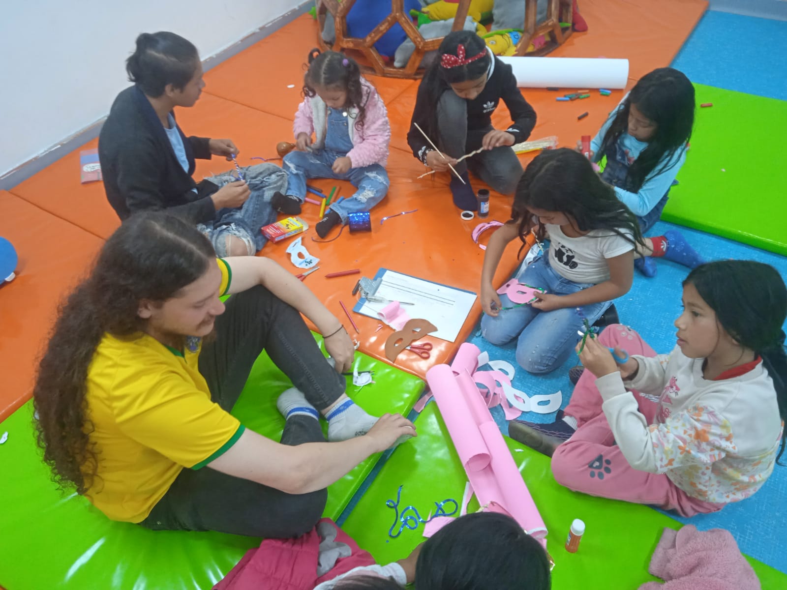 grupo de niños y niñas en medio de un taller de manualidades.