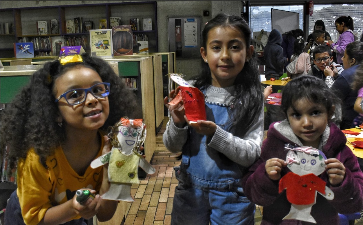 niñas mostrando las muñecas de papel que hicieron en un taller de manualidades