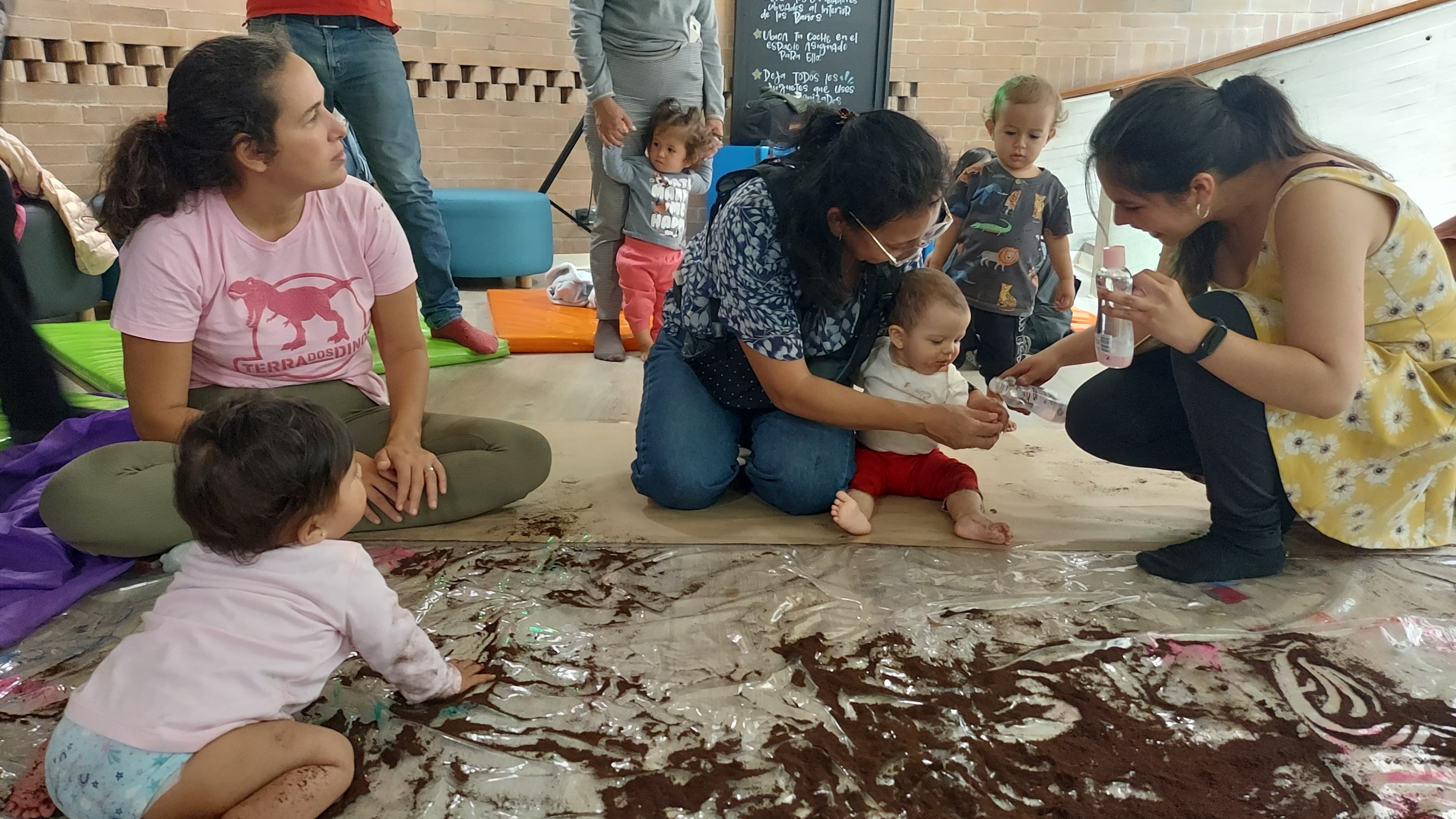 bebé jugando con tierra junto a su mamá