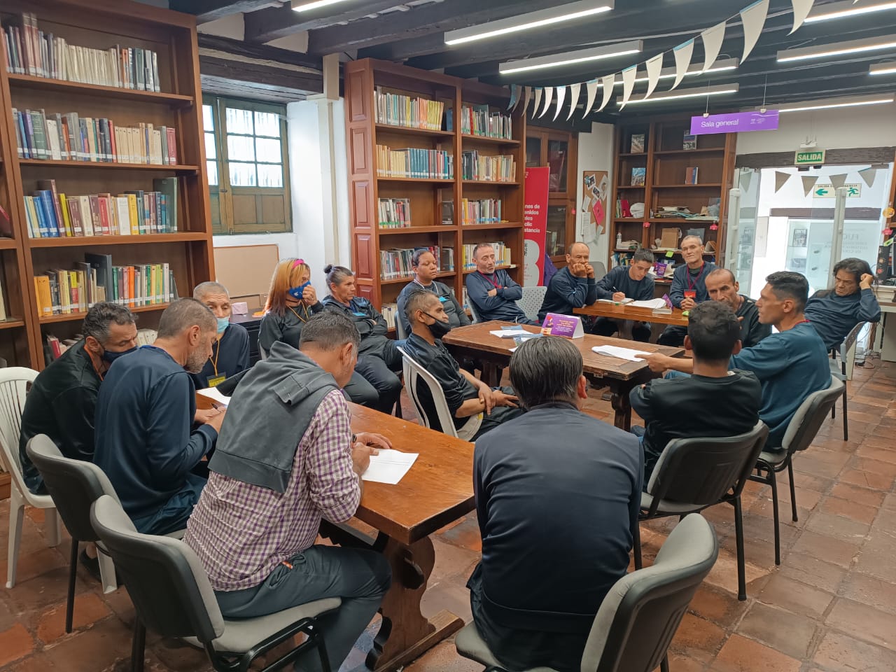 grupo de personas dialogando en medio de una sala de biblioteca