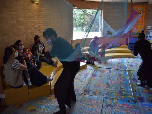 Cuidadores y sus bebés participando en experiencias lúdicas y sensoriales en la biblioteca