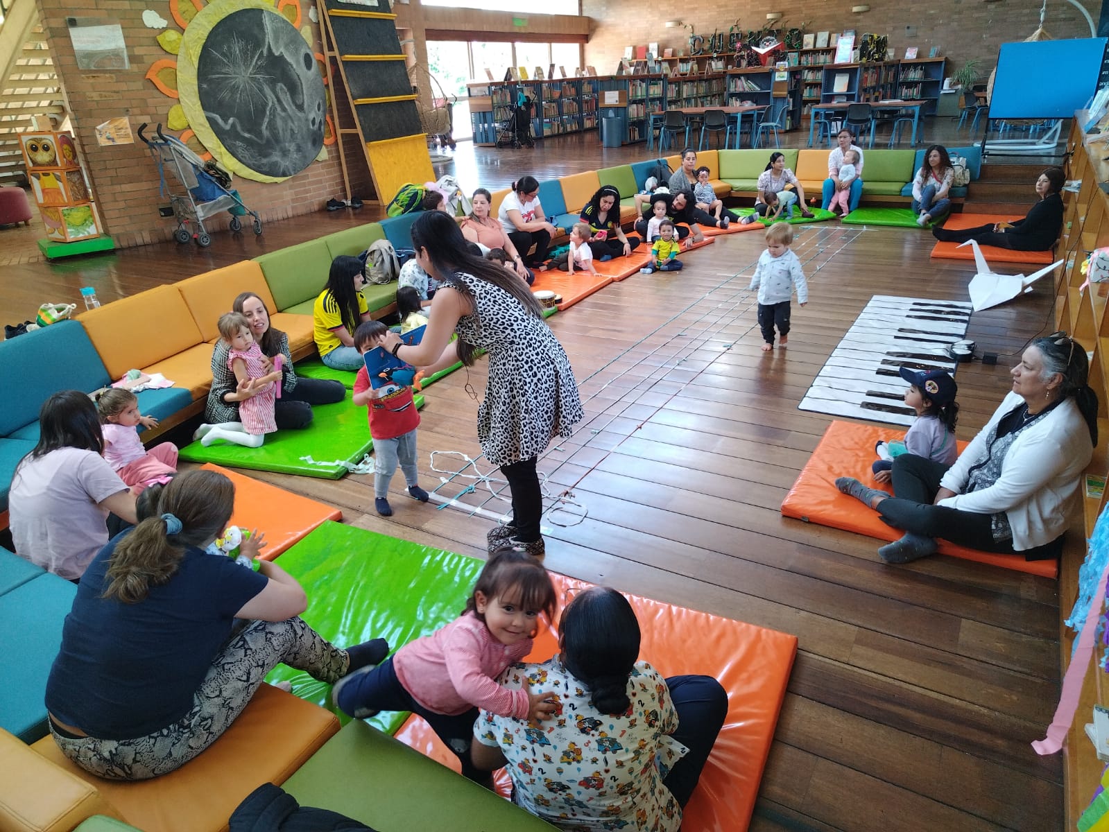 niños y niñas jugando y leyendo junto  a sus padres y madres 