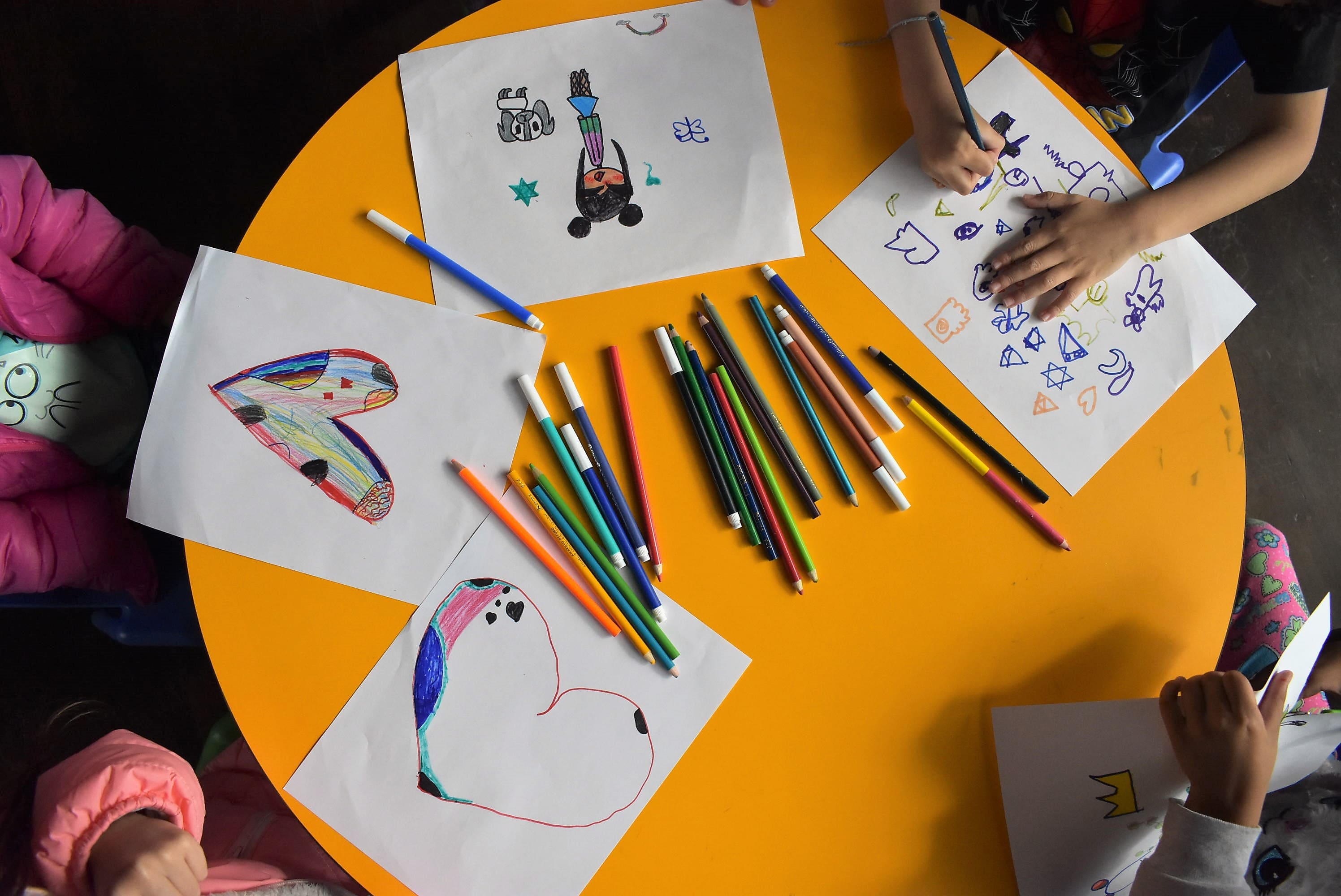 Niños pintando con colores en hojas de papel en la biblioteca