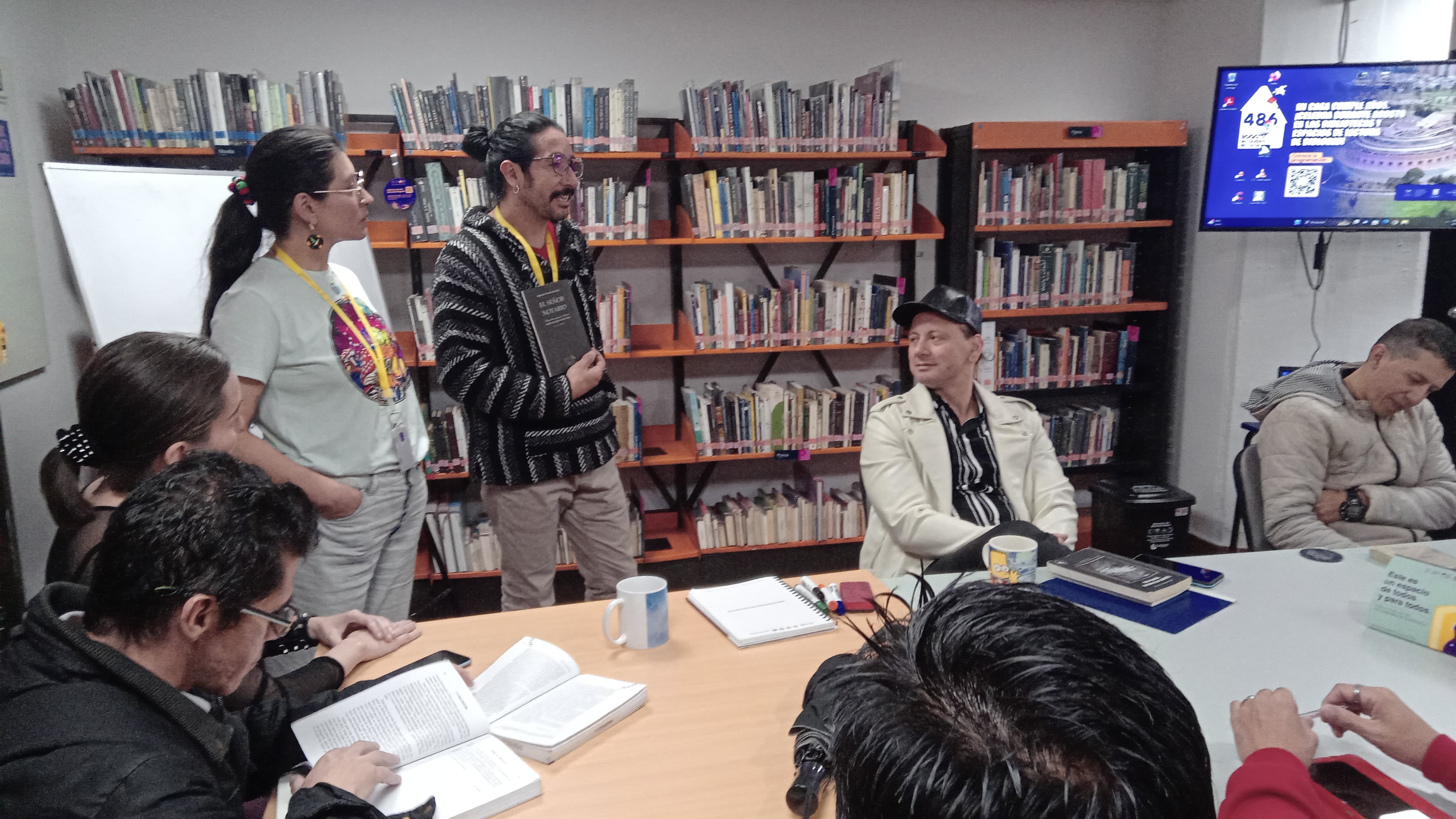 grupo de adultos reunidos y dialogando en torno a un libro