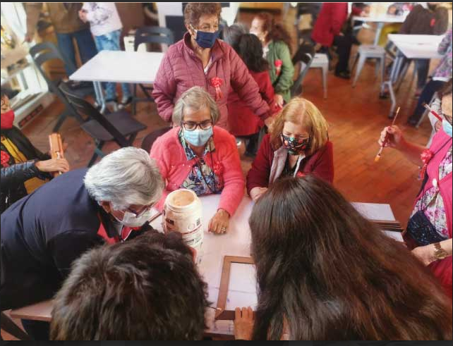 grupo de adultos mayores en medio de un taller de manualidades