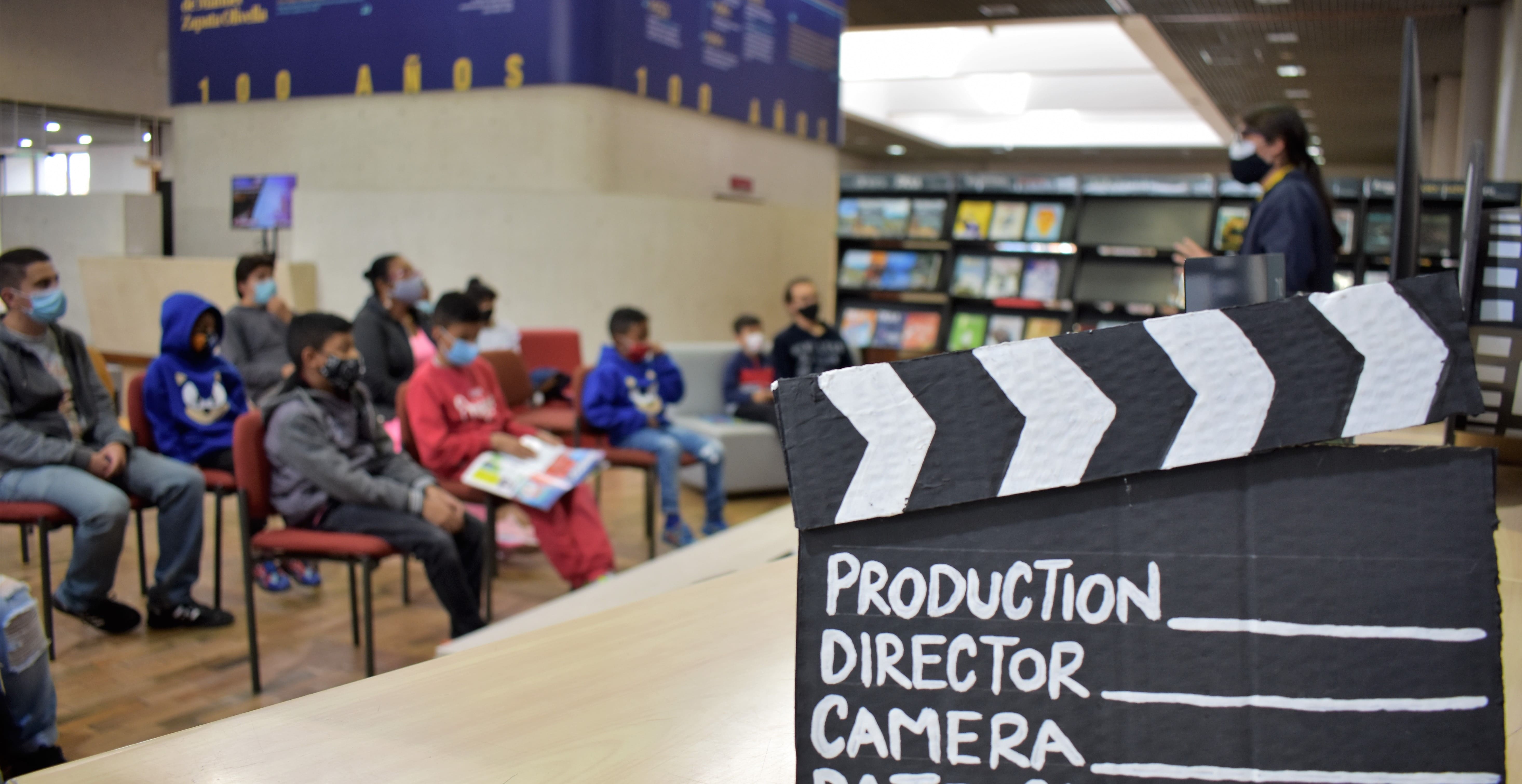 Sala de cine de la biblioteca con usuarios viendo una proyección cinematográfica. Claqueta