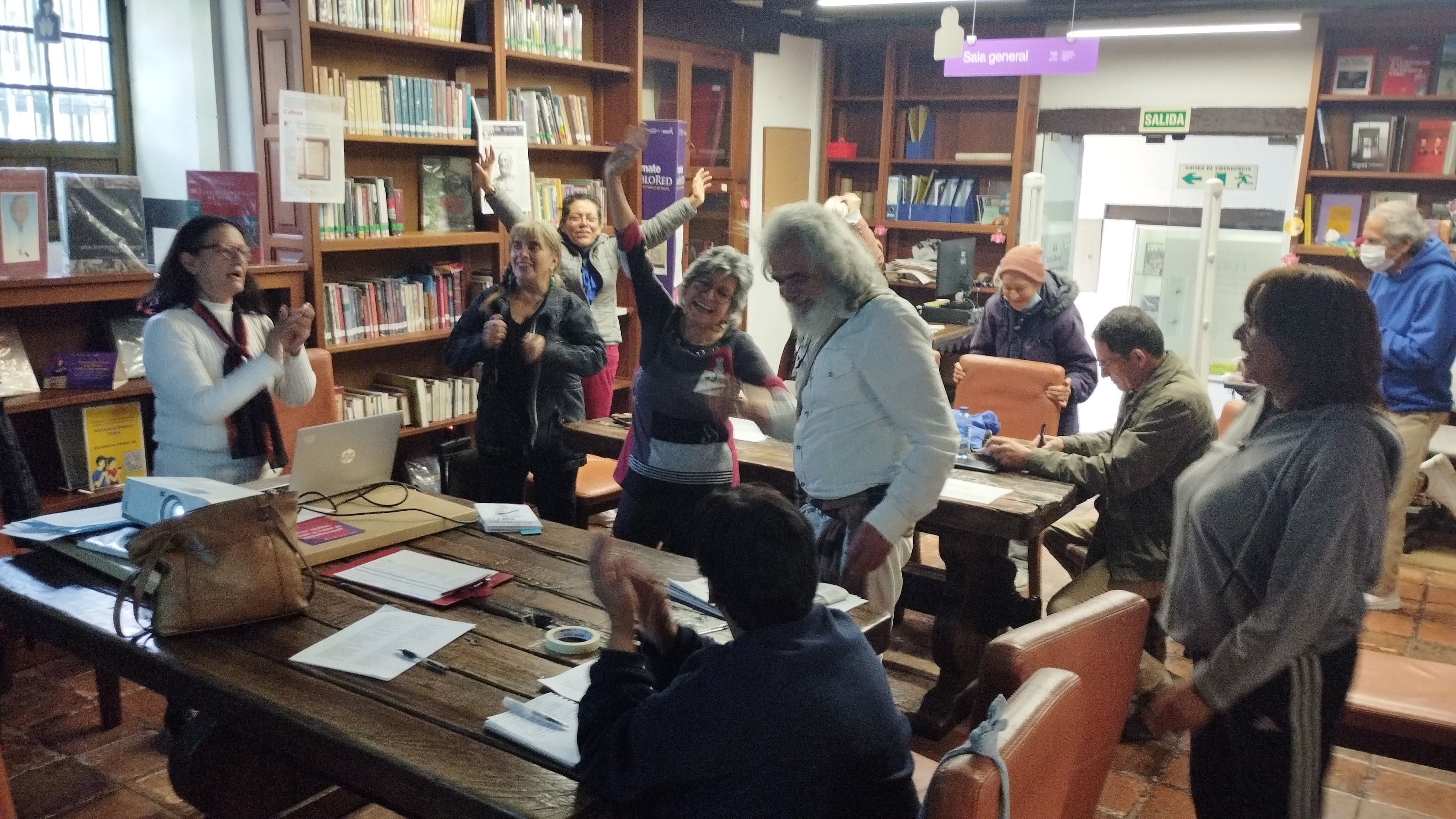 grupo de adultos bailando en medio de una biblioteca