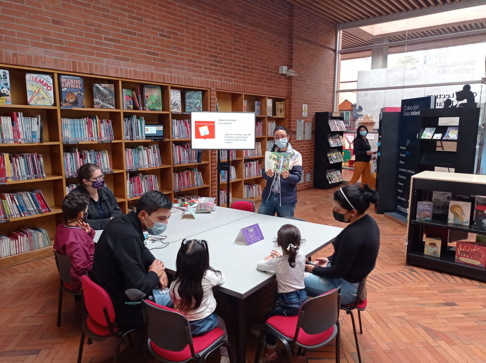 grupo de niños y niñas junto a sus padres y madres disfrutando de lecturas en voz alta