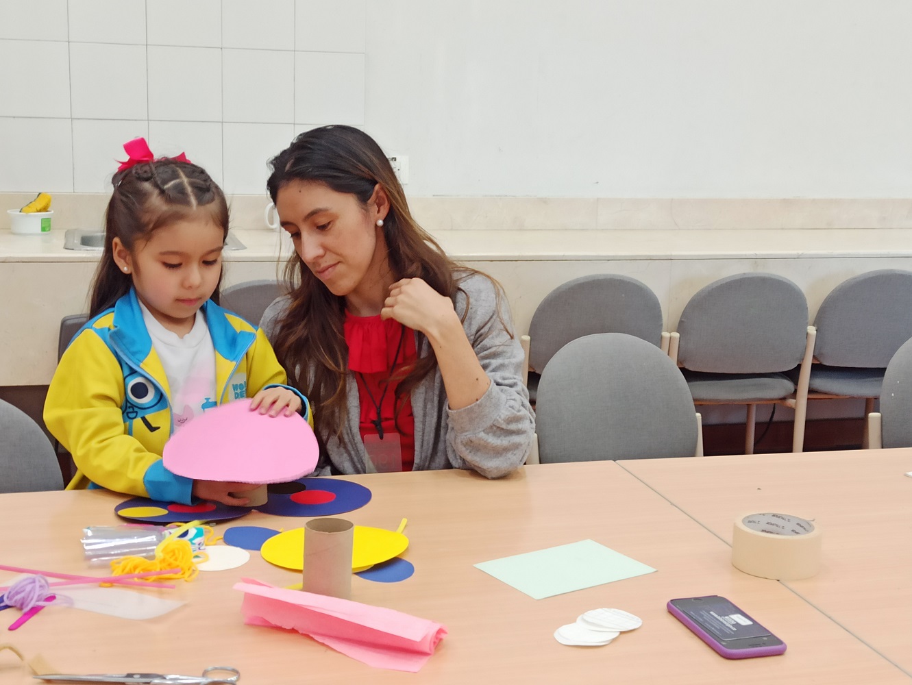 Cuidadora y niña participando en experiencias artísticas en la biblioteca