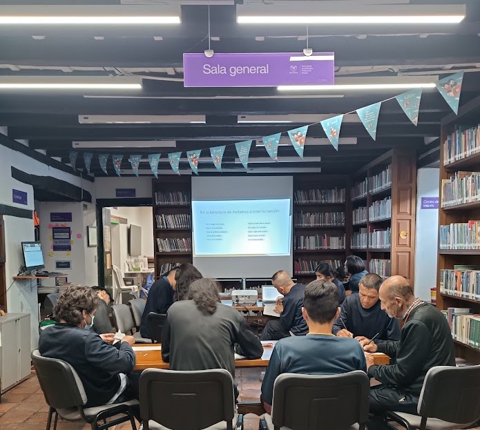 grupo de personas reunidas conversando en medio del salón de una biblioteca