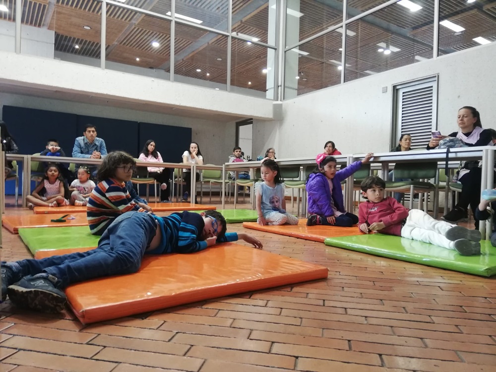 grupo de niños y niñas acostados sobre colchonetas de colores