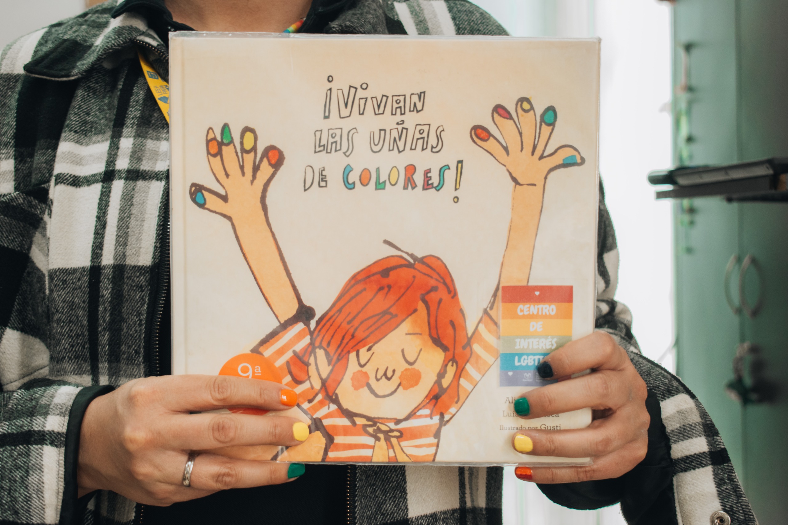 persona mostrando la portada de un libro llamado ¡Vivan las uñas de colores!