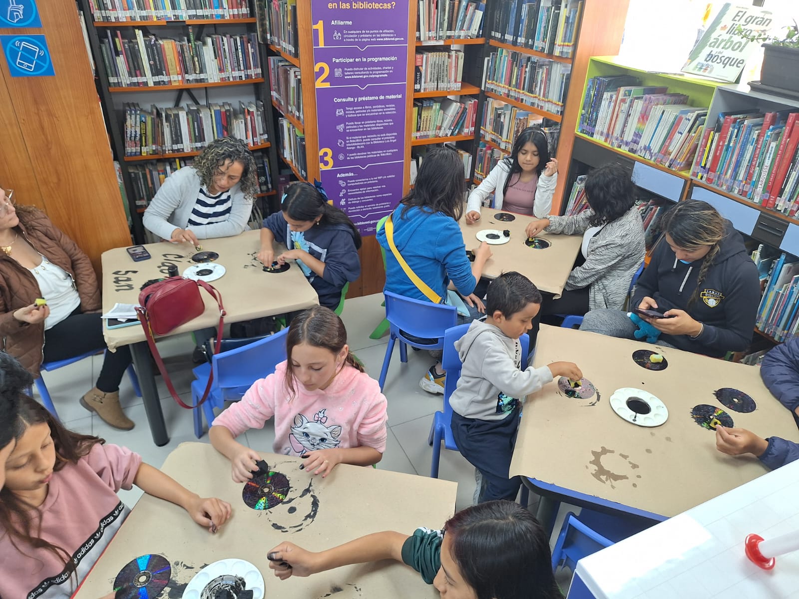 Infancia junto a sus cuidadores participando en el club de lectura en la biblioteca