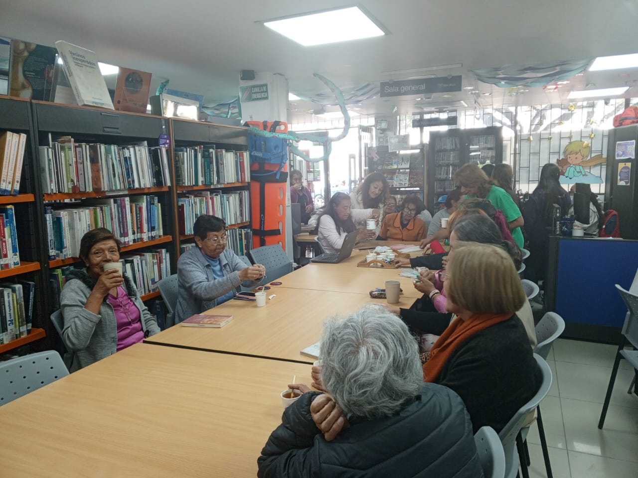 grupo de adultos mayores tomando café en medio de un taller de manualidades