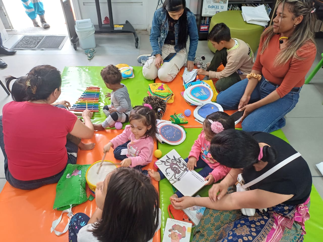 grupo de niños y niñas junto a sus padres jugando y leyendo