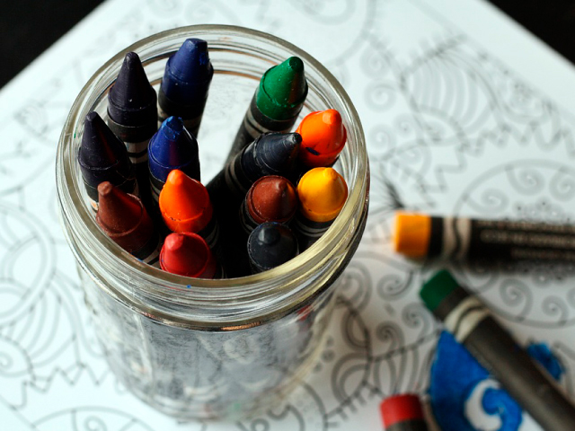 vaso de vidrio lleno de crayolas de colores