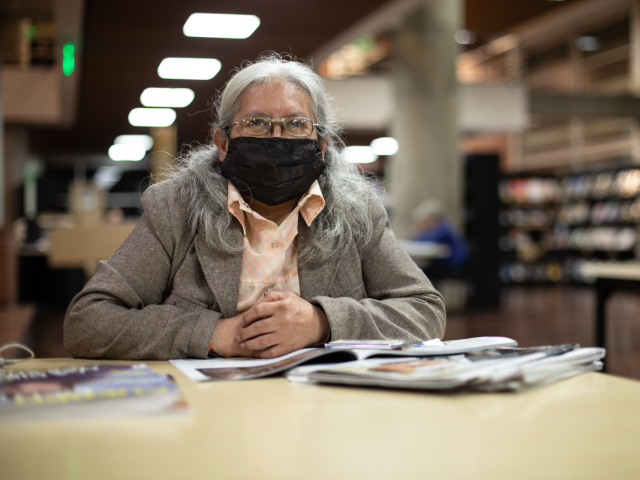 con adulto sentado en la biblioteca con libros frente a ella 