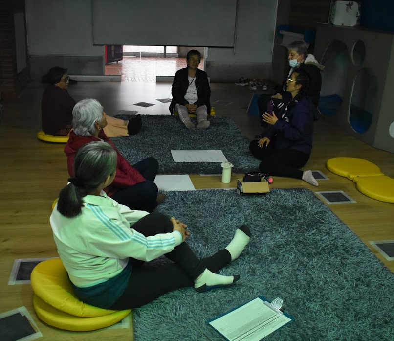 mujeres sentadas en el suelo sobre una alfombra leyendo y conversando