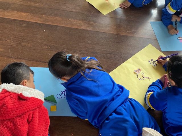 Infancia dibujando en hojas de colores en la biblioteca