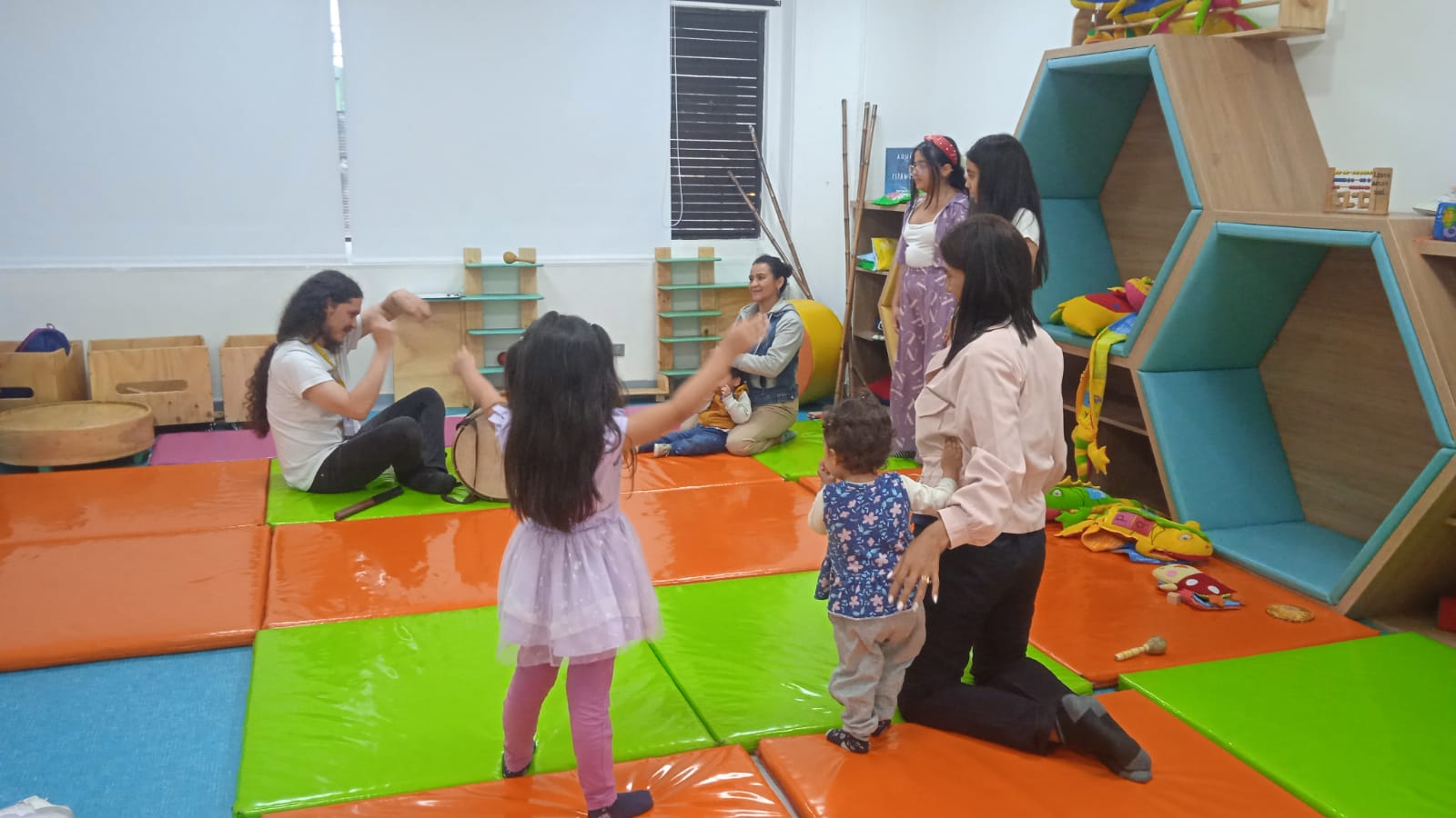 grupo de niñas y niños jugando junto a sus padres y madres 