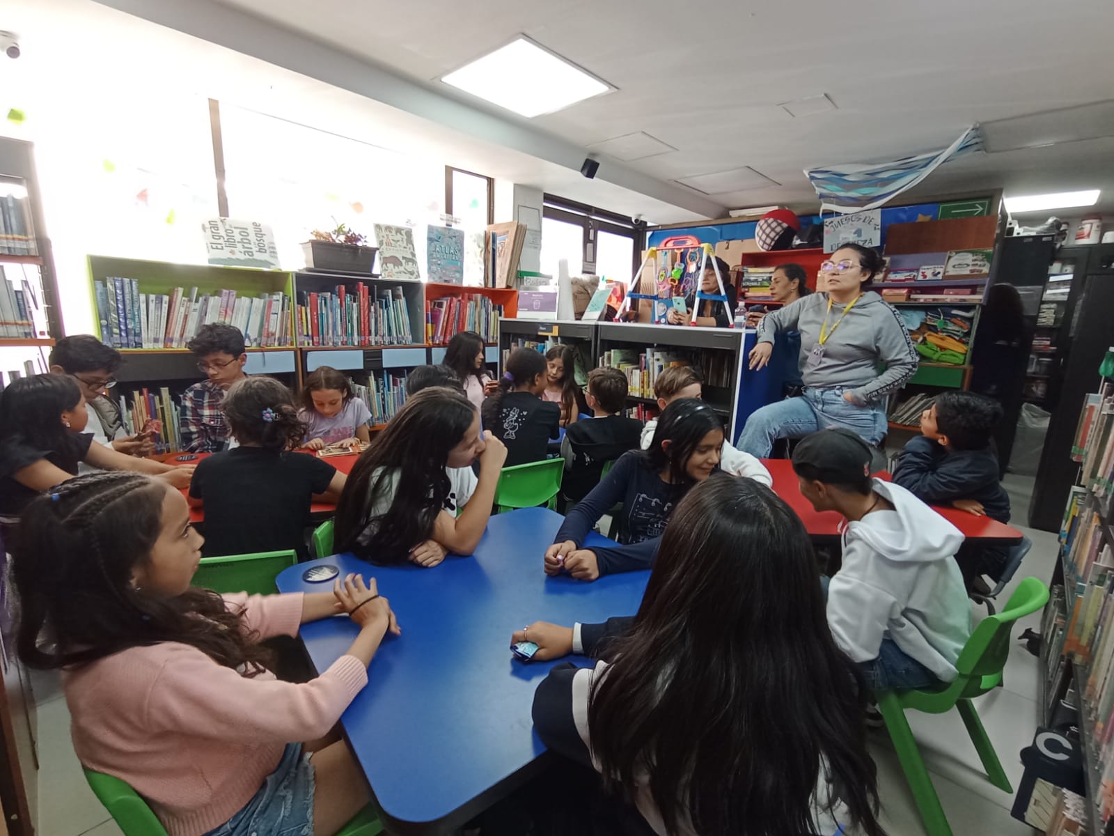 grupo grande de niños y niñas conversando entre ellos y con su docente